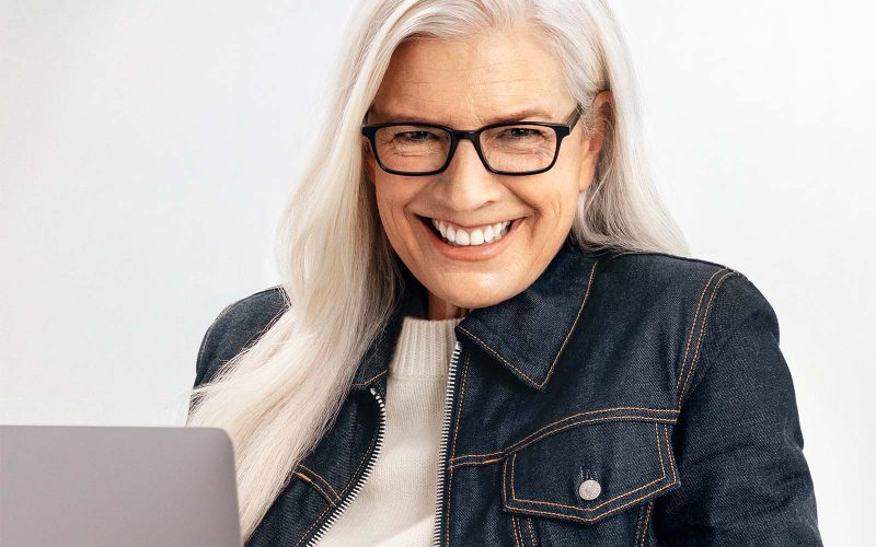 Woman wearing reading glasses and with laptop on her lap