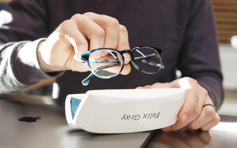 Someone holding a pair of black and blue glasses above a case