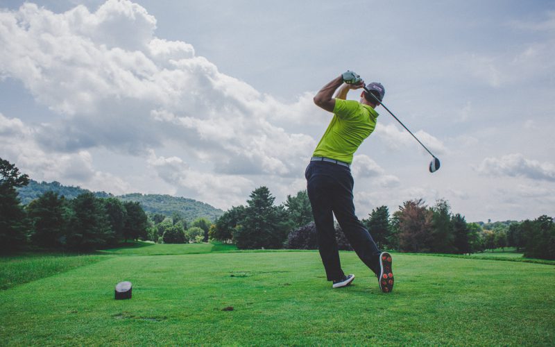 Man swinging a golf club on a golf course