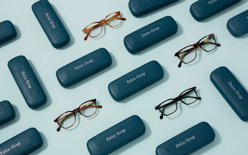A variety of eyeglasses and teal cases on a blue background