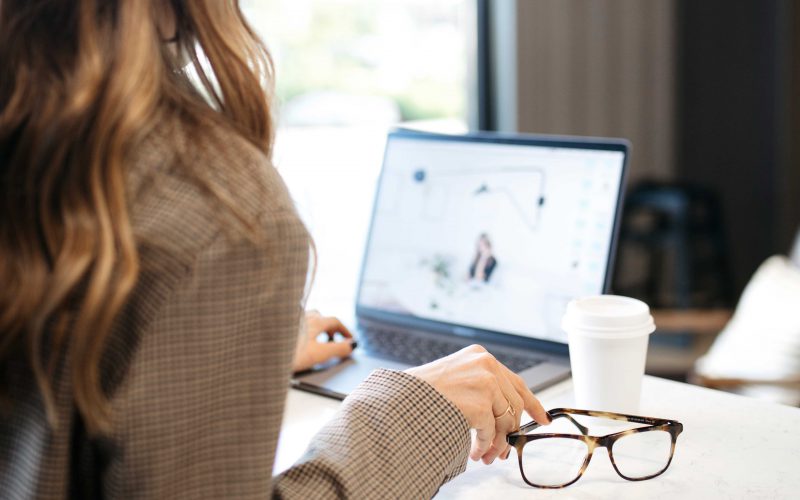 Woman working on her computer with her Felix Gray glasses next to her