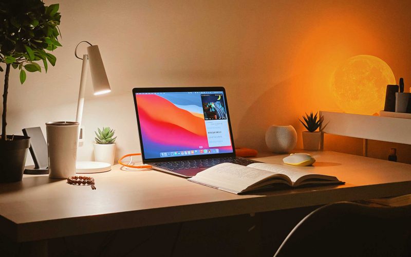 image of desk setup with lamp, computer, and book