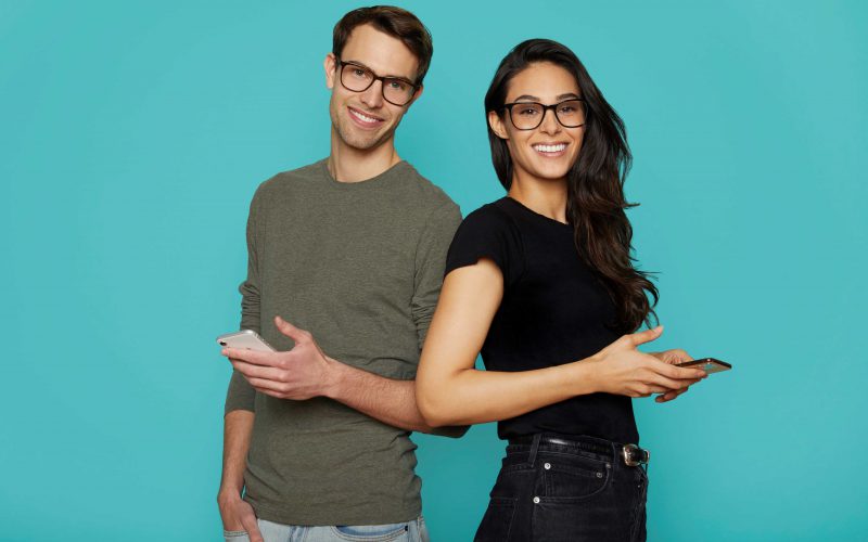 Man and women wearing Felix Gray's Volta oversized glasses with their phones